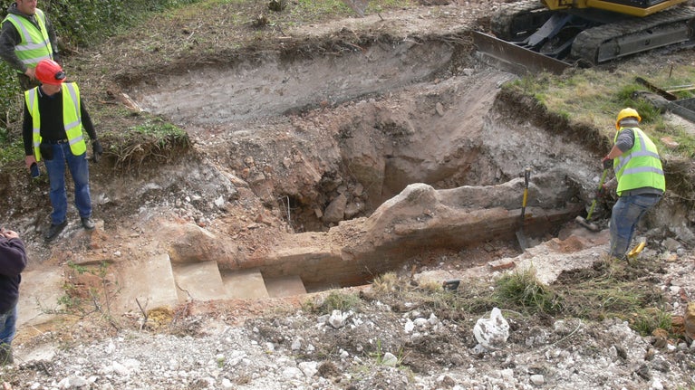 Image of 2 people working in an excavation uncovering a staircase that had been buried